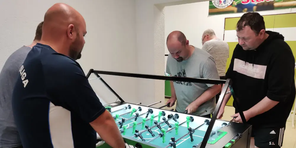 Bild vom Vereinsabend. Mehrere Personen die Tischfussball spielen